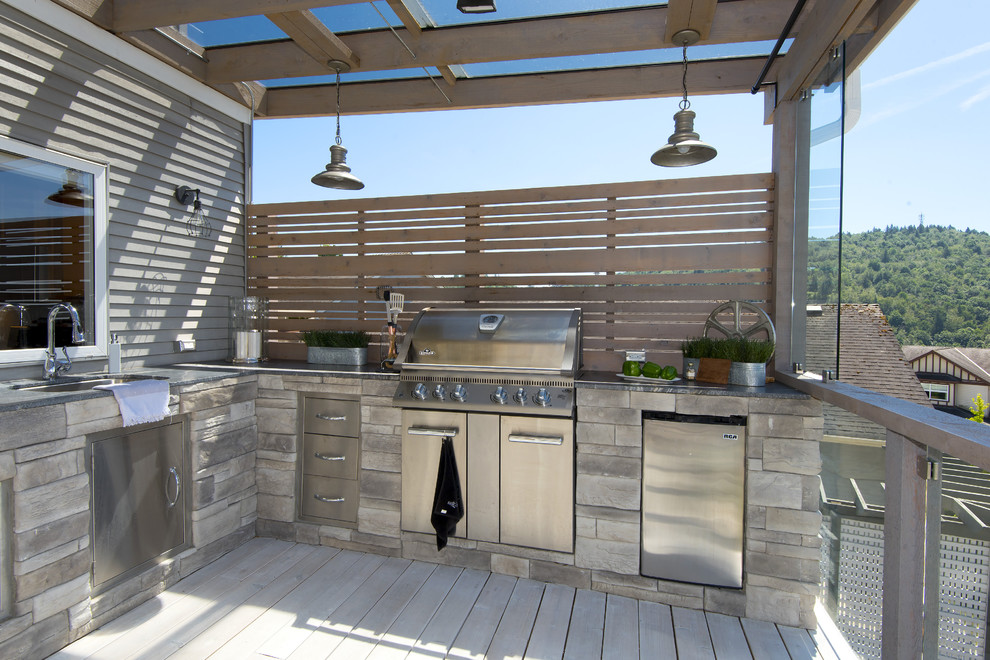 Example of a large transitional backyard outdoor kitchen deck design in Vancouver with a pergola