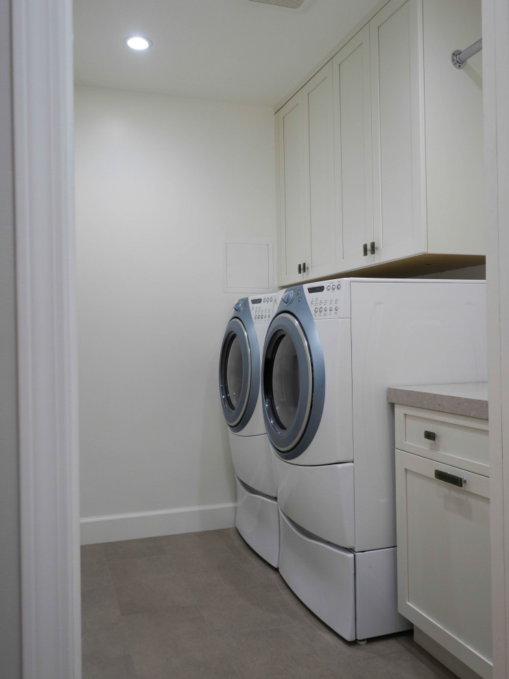 Photo of a mid-sized tropical laundry room in San Francisco with shaker cabinets, brown cabinets, white walls, porcelain floors and beige floor.