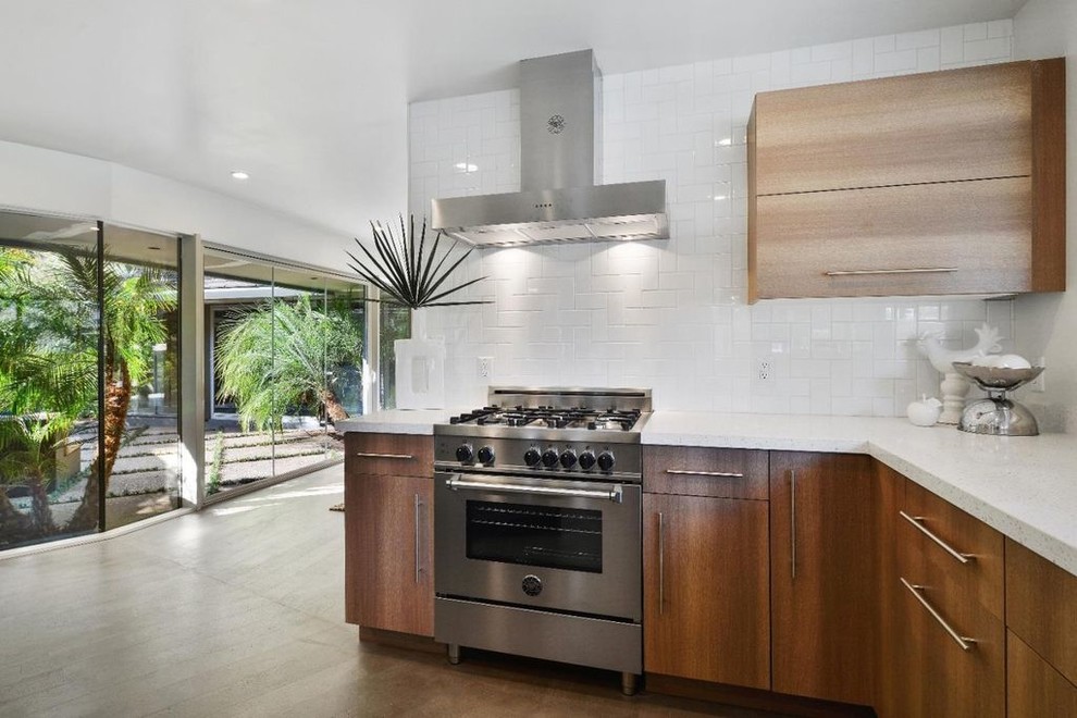 Inspiration for a mid-sized midcentury u-shaped eat-in kitchen in San Francisco with an undermount sink, flat-panel cabinets, medium wood cabinets, terrazzo benchtops, white splashback, ceramic splashback, stainless steel appliances, light hardwood floors, with island, grey floor and white benchtop.