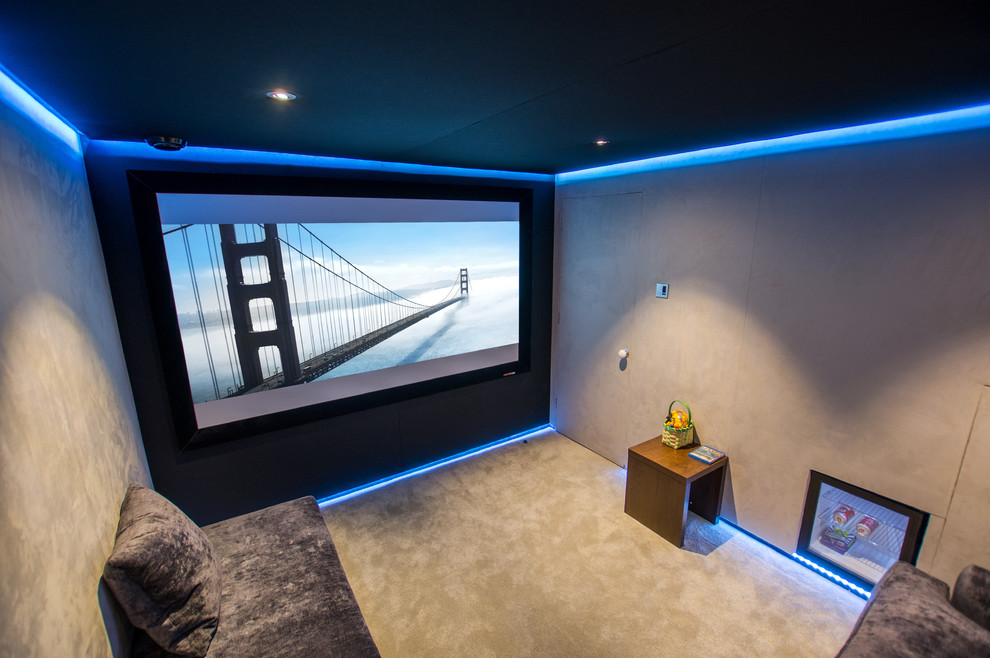 This is an example of a small contemporary enclosed home theatre in London with beige walls, carpet and a projector screen.