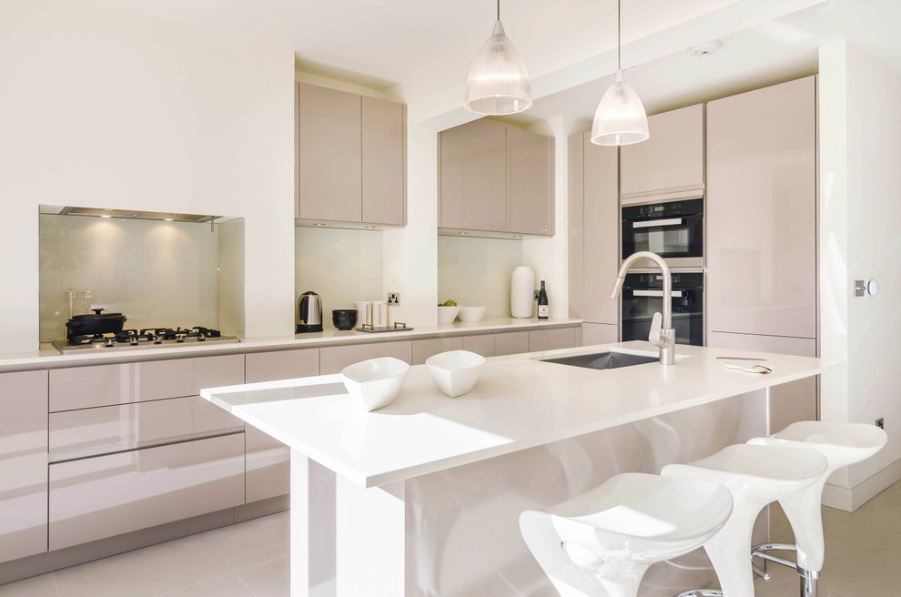 Design ideas for a mid-sized contemporary l-shaped kitchen in London with an undermount sink, flat-panel cabinets, beige cabinets, quartzite benchtops, beige splashback, glass sheet splashback, panelled appliances, porcelain floors and a peninsula.