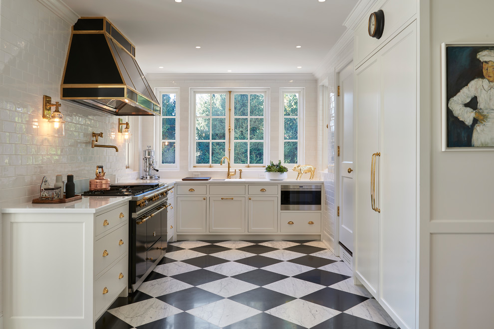 Design ideas for a transitional kitchen in New York with recessed-panel cabinets, solid surface benchtops, ceramic splashback, black appliances, marble floors and white benchtop.