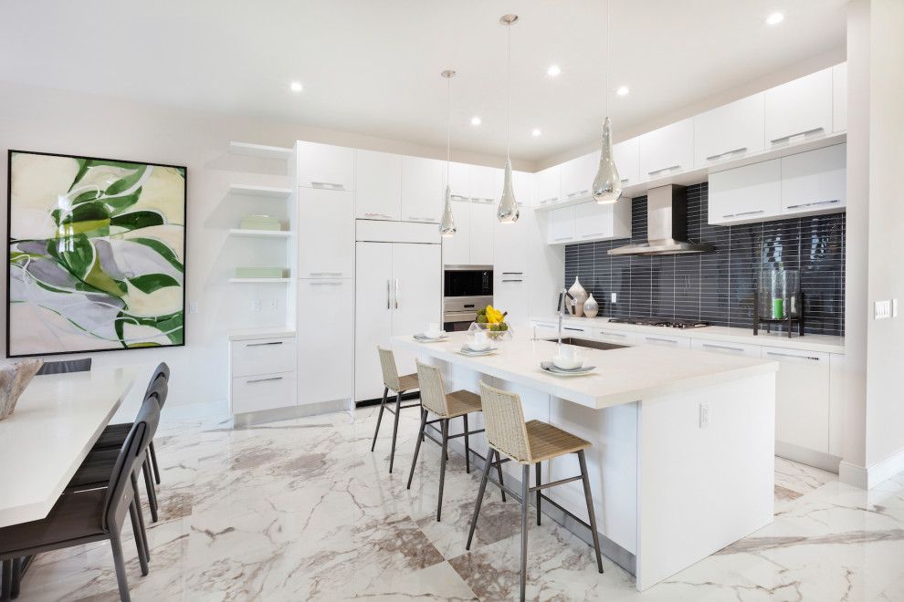 Small contemporary l-shaped eat-in kitchen in Miami with a drop-in sink, flat-panel cabinets, white cabinets, granite benchtops, black splashback, ceramic splashback, panelled appliances, marble floors, with island, multi-coloured floor and white benchtop.