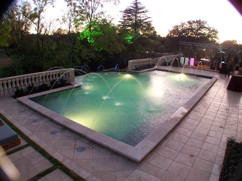 Design ideas for a large mediterranean backyard rectangular infinity pool in Dallas with a water feature and tile.