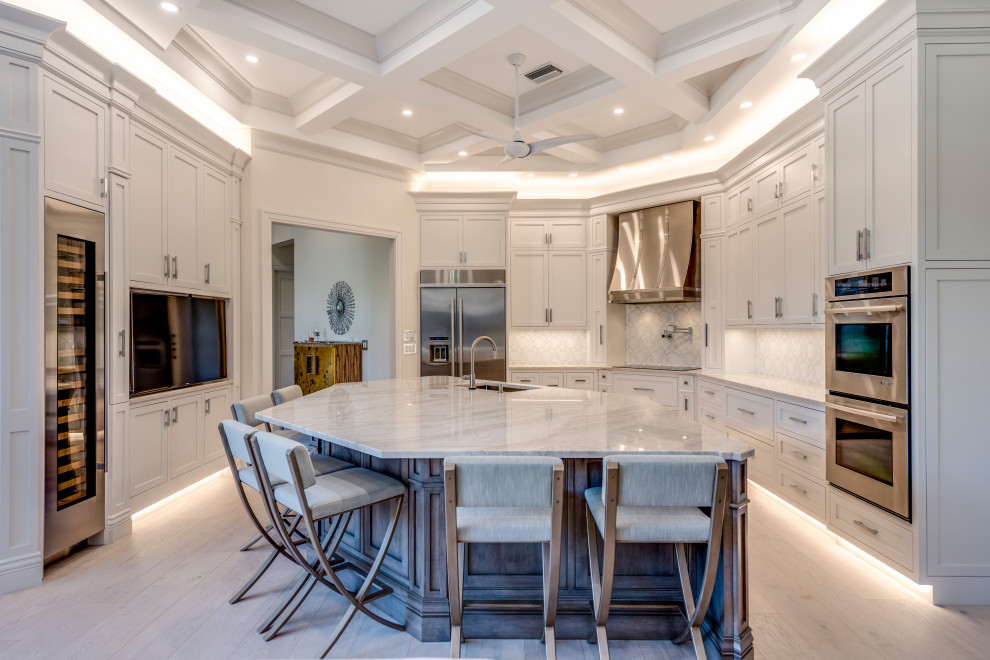 Inspiration for a transitional u-shaped light wood floor, beige floor and coffered ceiling open concept kitchen remodel with an undermount sink, beaded inset cabinets, white cabinets, quartzite countertops, white backsplash, stone tile backsplash, stainless steel appliances, an island and gray countertops