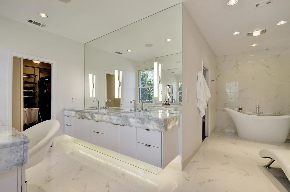 This is an example of a mid-sized contemporary master bathroom in Austin with an undermount sink, flat-panel cabinets, white cabinets, quartzite benchtops, a freestanding tub, white tile and white walls.