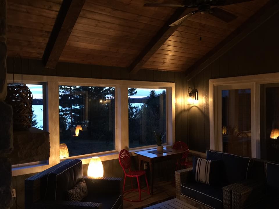 Mid-sized mountain style sunroom photo with a wood stove, a stone fireplace and a standard ceiling