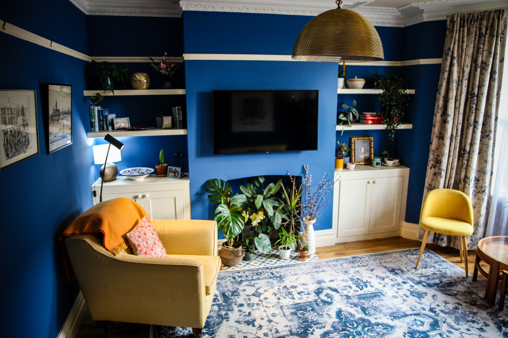 Idée de décoration pour un grand salon minimaliste fermé avec un mur bleu, parquet clair, aucune cheminée, un manteau de cheminée en plâtre, un téléviseur fixé au mur et un sol marron.