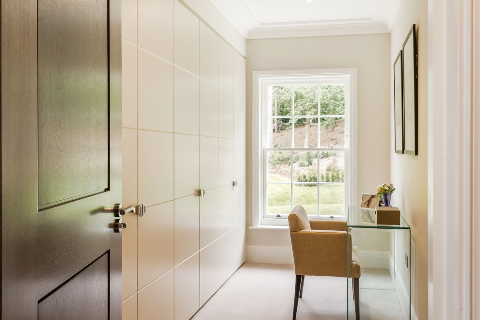 Transitional gender-neutral dressing room in Surrey with flat-panel cabinets, white cabinets and carpet.