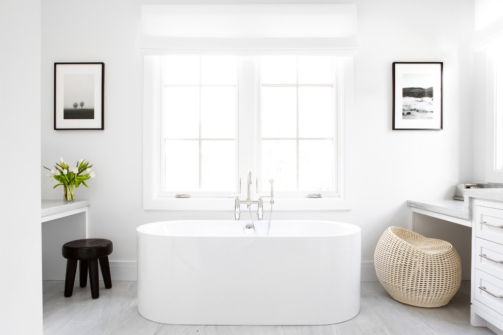 This is an example of a mid-sized country master bathroom in New York with shaker cabinets, white cabinets, a freestanding tub, white walls, grey floor and grey benchtops.