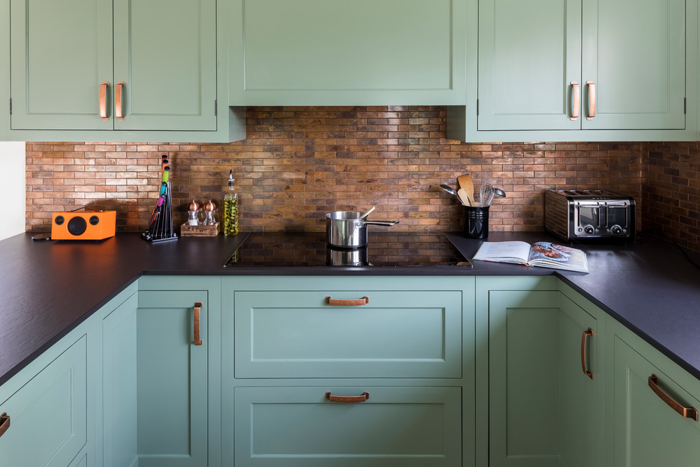Photo of a mid-sized traditional u-shaped eat-in kitchen in Kent with a farmhouse sink, shaker cabinets, green cabinets, quartz benchtops, metal splashback, linoleum floors, a peninsula and green floor.