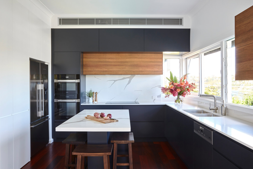 This is an example of a mid-sized modern u-shaped separate kitchen in Sydney with a double-bowl sink, flat-panel cabinets, blue cabinets, quartz benchtops, white splashback, engineered quartz splashback, dark hardwood floors, with island, brown floor and white benchtop.