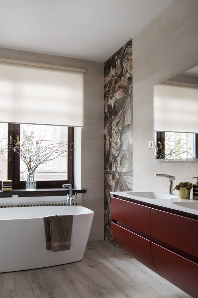Пример оригинального дизайна: большая главная ванная комната в современном стиле с плоскими фасадами, красными фасадами, отдельно стоящей ванной, душем в нише, инсталляцией, керамогранитной плиткой, бежевыми стенами, полом из керамогранита, монолитной раковиной, столешницей из искусственного кварца, бежевым полом, душем с распашными дверями, белой столешницей, окном, тумбой под одну раковину и подвесной тумбой
