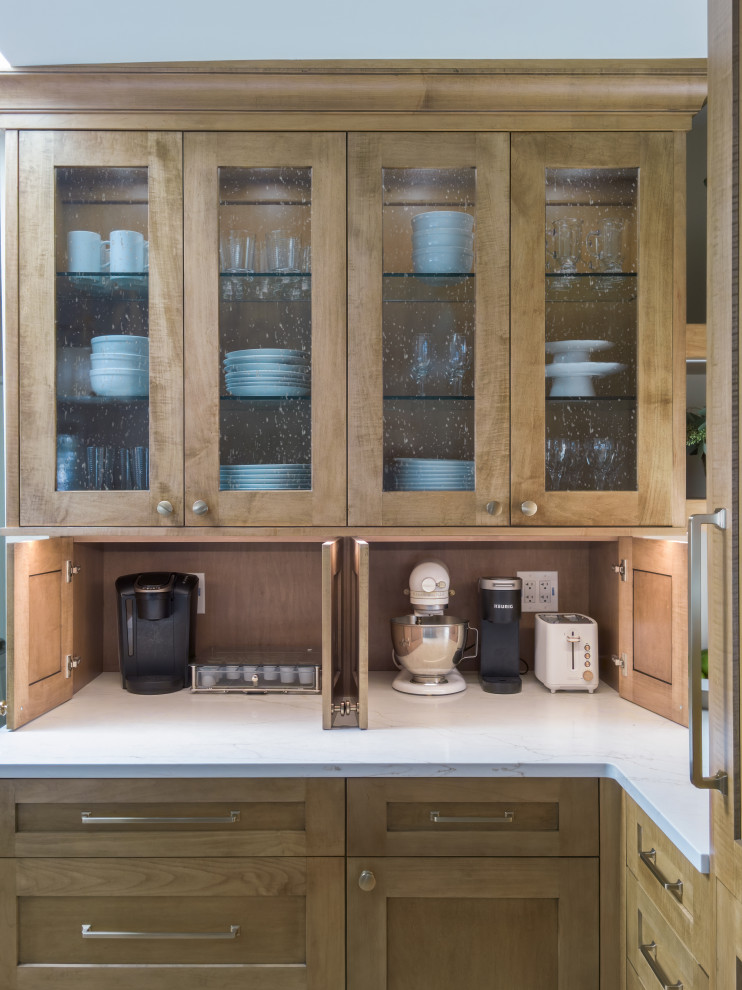 Mid-sized transitional l-shaped medium tone wood floor and brown floor open concept kitchen photo in Chicago with an undermount sink, glass-front cabinets, medium tone wood cabinets, quartz countertops, white backsplash, ceramic backsplash, stainless steel appliances, an island and white countertops
