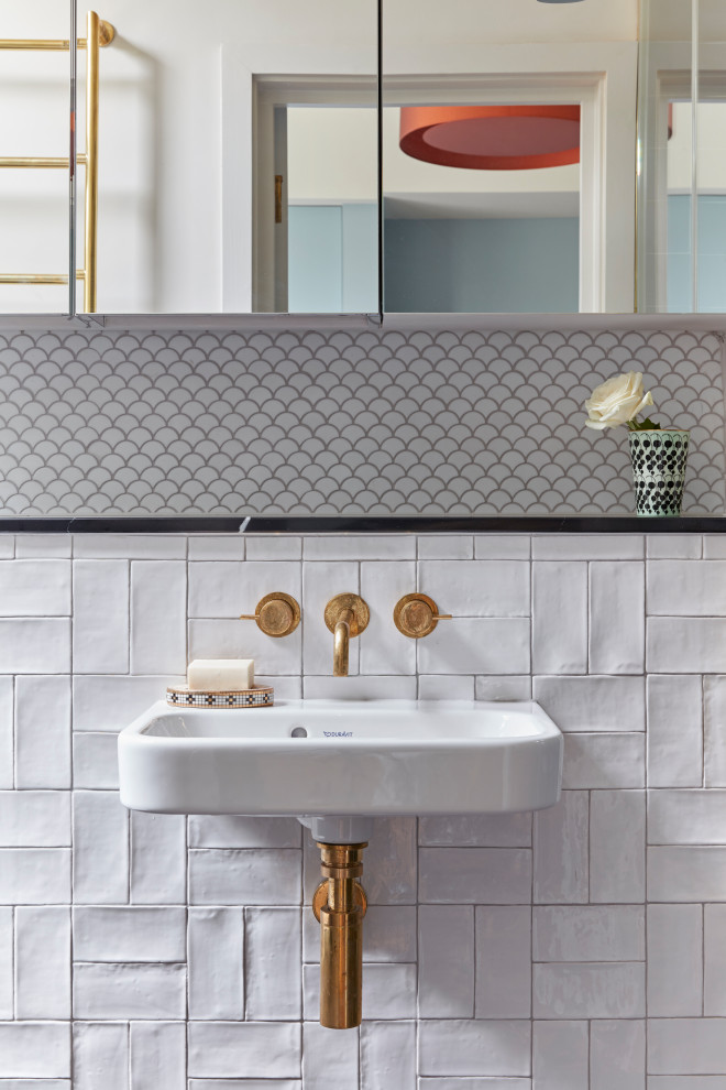 This is an example of a traditional bathroom in London with white tile, a wall-mount sink and a single vanity.