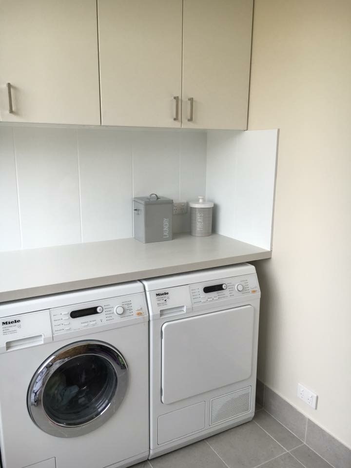 Example of a small transitional single-wall ceramic tile dedicated laundry room design in Perth with flat-panel cabinets, beige cabinets, solid surface countertops, beige walls and a side-by-side washer/dryer