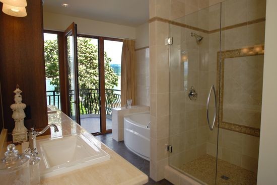 Inspiration for a mid-sized mediterranean master bathroom in Vancouver with shaker cabinets, dark wood cabinets, an alcove tub, an alcove shower, ceramic tile, beige walls, ceramic floors, a drop-in sink, limestone benchtops, brown floor and a hinged shower door.