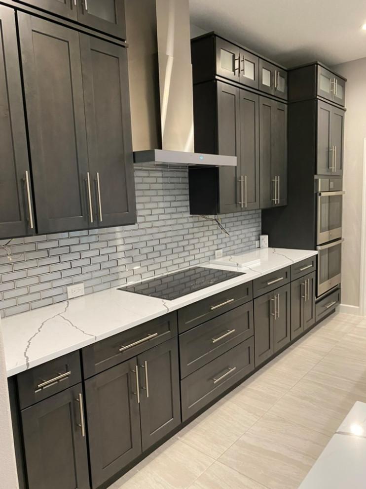Inspiration for a large transitional porcelain tile and beige floor eat-in kitchen remodel in Tampa with a single-bowl sink, shaker cabinets, dark wood cabinets, quartzite countertops, gray backsplash, subway tile backsplash, stainless steel appliances, an island and white countertops