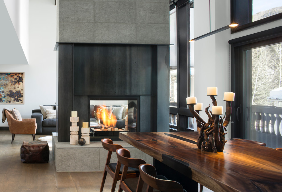 Photo of a modern dining room in Denver with a two-sided fireplace and a metal fireplace surround.