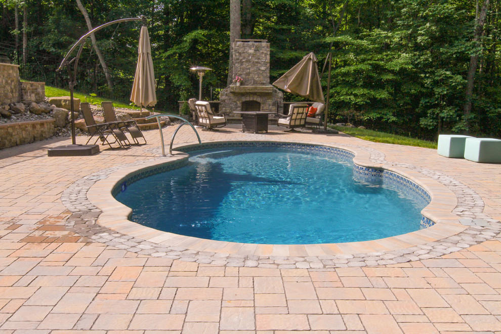 Large traditional backyard custom-shaped natural pool in Other with natural stone pavers.