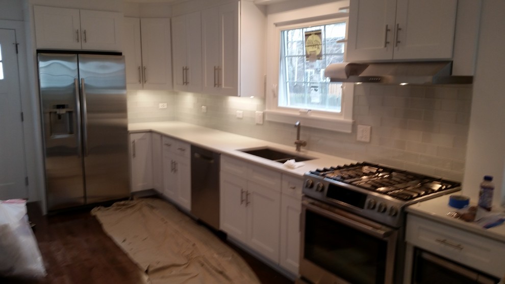 Inspiration for a mid-sized modern galley dark wood floor eat-in kitchen remodel with an undermount sink, recessed-panel cabinets, white cabinets, granite countertops, white backsplash, glass tile backsplash, stainless steel appliances and a peninsula