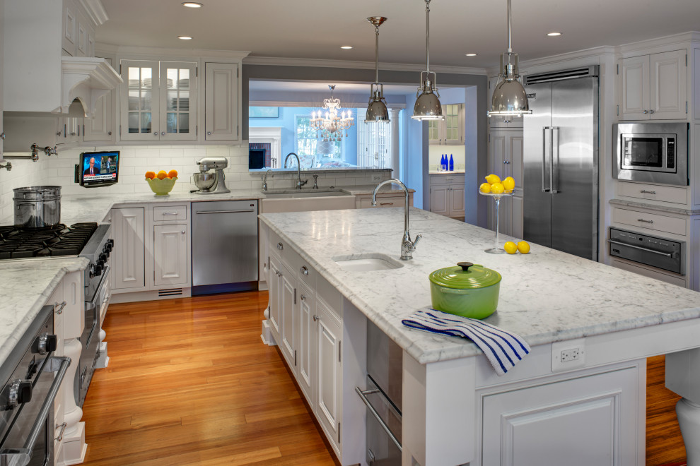Example of a transitional medium tone wood floor and brown floor eat-in kitchen design in Baltimore with white cabinets, marble countertops, white backsplash, stainless steel appliances, an island and white countertops