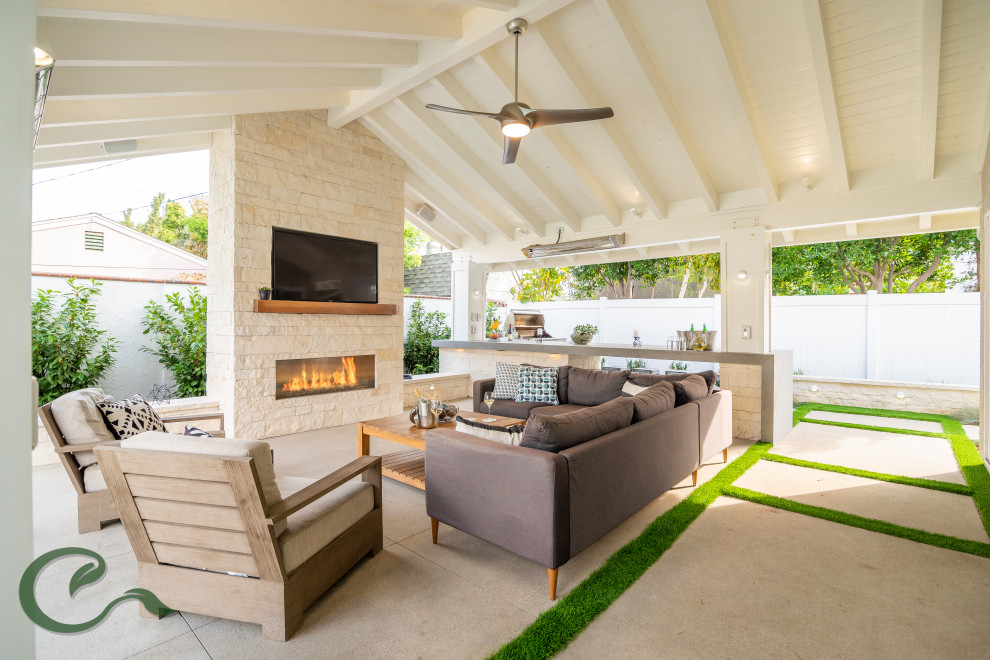 Photo of a mid-sized contemporary backyard patio in Orange County with with fireplace, concrete slab and a roof extension.