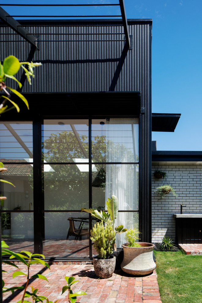 На фото: одноэтажный, деревянный, черный частный загородный дом среднего размера в современном стиле с крышей-бабочкой, металлической крышей и черной крышей с