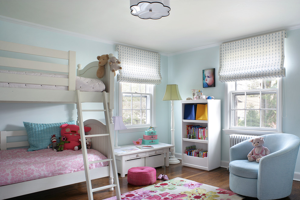 Photo of a mid-sized transitional kids' bedroom for kids 4-10 years old and girls in New York with blue walls and dark hardwood floors.
