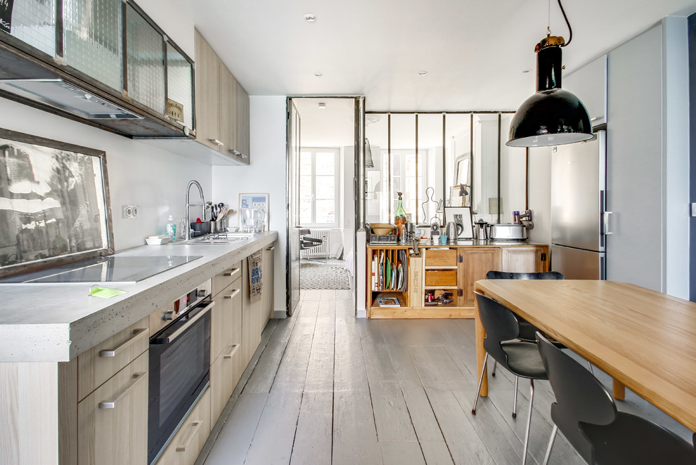 This is an example of a scandinavian eat-in kitchen in Le Havre with flat-panel cabinets, light wood cabinets, concrete benchtops, painted wood floors, beige floor and grey benchtop.