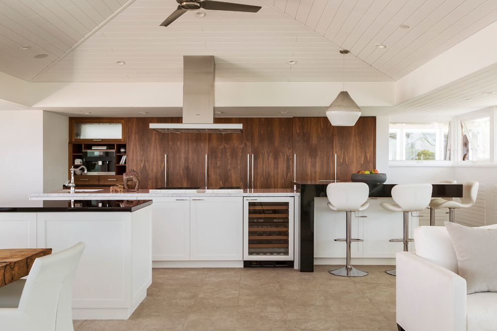 Inspiration for a large contemporary u-shaped eat-in kitchen in Los Angeles with flat-panel cabinets, medium wood cabinets, stainless steel appliances, multiple islands, a farmhouse sink, granite benchtops and light hardwood floors.