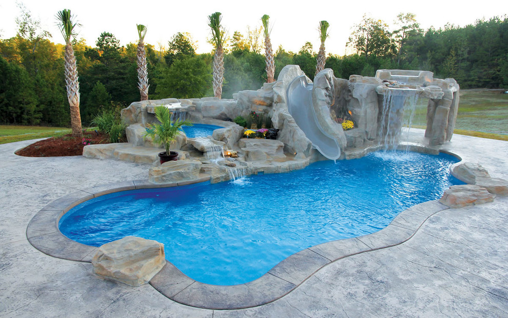 Photo of a large beach style backyard custom-shaped natural pool in Other with a water feature and stamped concrete.