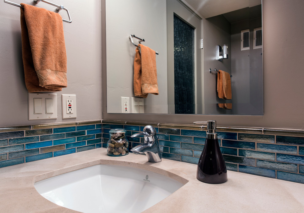 Mid-sized modern master bathroom in San Diego with an undermount sink, recessed-panel cabinets, white cabinets, limestone benchtops, blue tile, glass tile, beige walls and limestone floors.