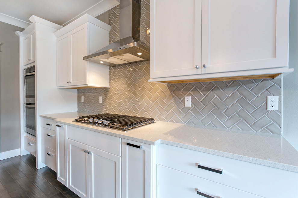 Example of a large transitional l-shaped medium tone wood floor open concept kitchen design in Seattle with an undermount sink, shaker cabinets, white cabinets, glass countertops, gray backsplash, glass tile backsplash, stainless steel appliances and an island