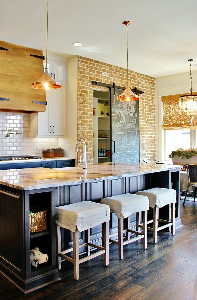 Photo of a transitional l-shaped eat-in kitchen in Nashville with a farmhouse sink, white cabinets, marble benchtops, white splashback, subway tile splashback, stainless steel appliances, dark hardwood floors and with island.
