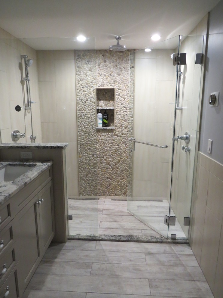 Inspiration for a mid-sized transitional master bathroom in Portland Maine with an undermount sink, recessed-panel cabinets, grey cabinets, granite benchtops, an alcove shower, a wall-mount toilet, multi-coloured tile, pebble tile, blue walls and porcelain floors.