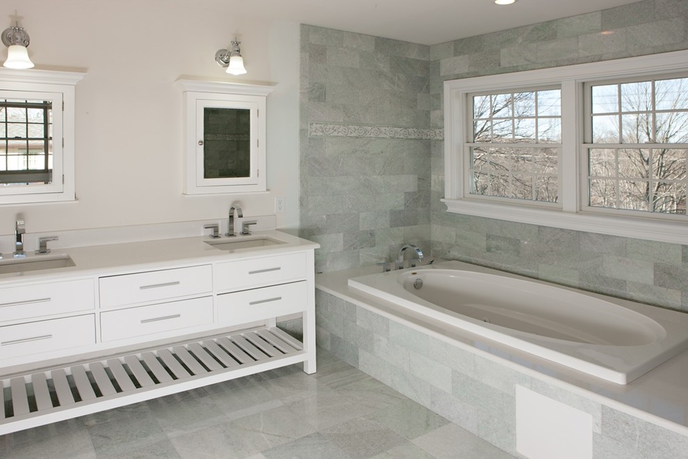 Photo of a large arts and crafts master bathroom in New York with furniture-like cabinets, white cabinets, quartzite benchtops, a drop-in tub, gray tile, white walls and mosaic tile floors.