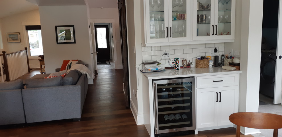 Example of an eclectic dark wood floor kitchen design in Toronto with shaker cabinets, white cabinets, quartzite countertops, white backsplash, subway tile backsplash, stainless steel appliances and white countertops