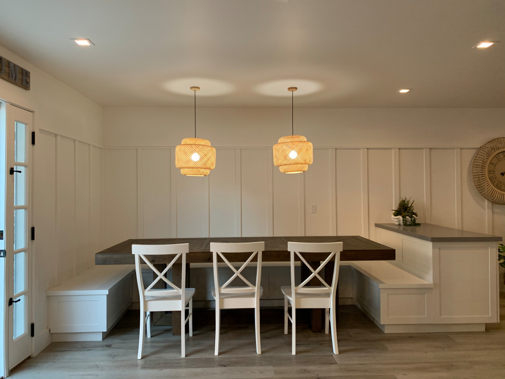 This is an example of a small beach style dining room in Orange County with white walls, vinyl floors, beige floor and panelled walls.