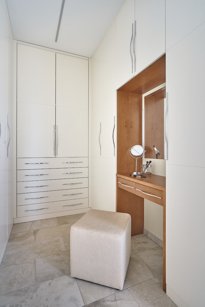 Photo of a contemporary gender-neutral dressing room in Other with flat-panel cabinets, white cabinets and grey floor.