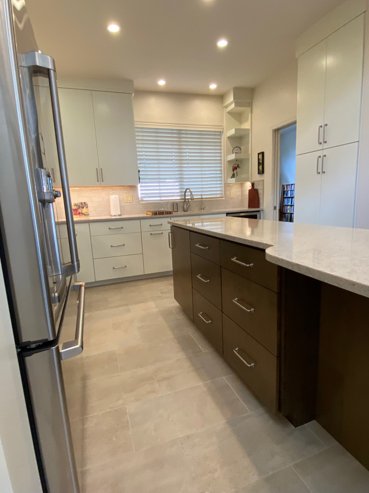 Mid-sized transitional l-shaped eat-in kitchen in Phoenix with an undermount sink, flat-panel cabinets, white cabinets, quartz benchtops, white splashback, porcelain splashback, stainless steel appliances, porcelain floors, with island, grey floor and white benchtop.