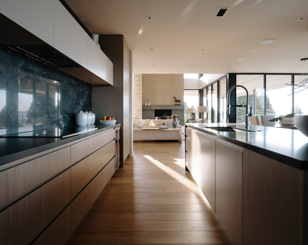 Photo of a large contemporary galley eat-in kitchen in Vancouver with an undermount sink, flat-panel cabinets, medium wood cabinets, quartz benchtops, grey splashback, porcelain splashback, stainless steel appliances, medium hardwood floors, with island and grey benchtop.