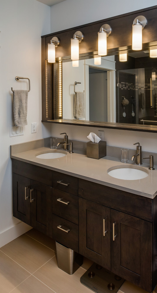 Photo of a small contemporary 3/4 bathroom in Other with recessed-panel cabinets, dark wood cabinets, an alcove shower, a two-piece toilet, gray tile, ceramic tile, grey walls, ceramic floors, an undermount sink and engineered quartz benchtops.