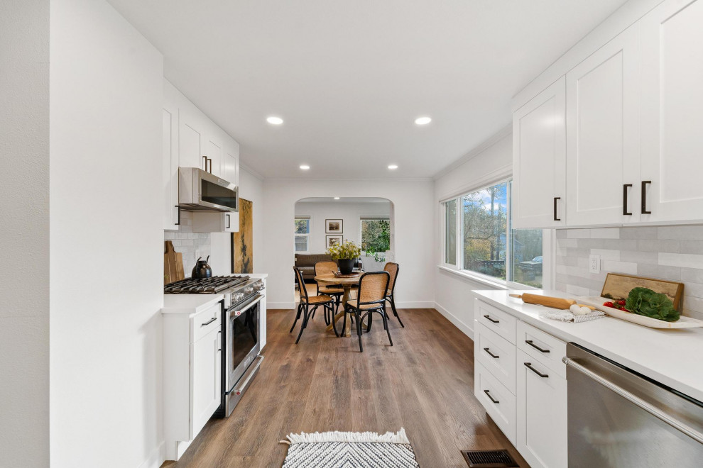 Inspiration for a transitional galley dark wood floor and brown floor eat-in kitchen remodel in Seattle with shaker cabinets, white cabinets, quartzite countertops, gray backsplash, ceramic backsplash, stainless steel appliances, no island, white countertops and an undermount sink