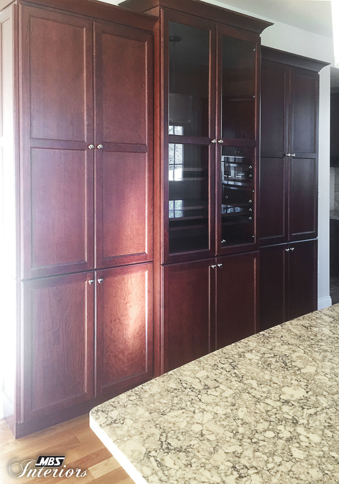 Eat-in kitchen - large transitional medium tone wood floor eat-in kitchen idea in Cincinnati with an undermount sink, recessed-panel cabinets, dark wood cabinets, quartz countertops, beige backsplash, stone tile backsplash, stainless steel appliances and an island