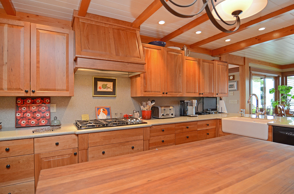 Large arts and crafts u-shaped eat-in kitchen in Seattle with a farmhouse sink, raised-panel cabinets, medium wood cabinets, granite benchtops, black appliances, medium hardwood floors and with island.