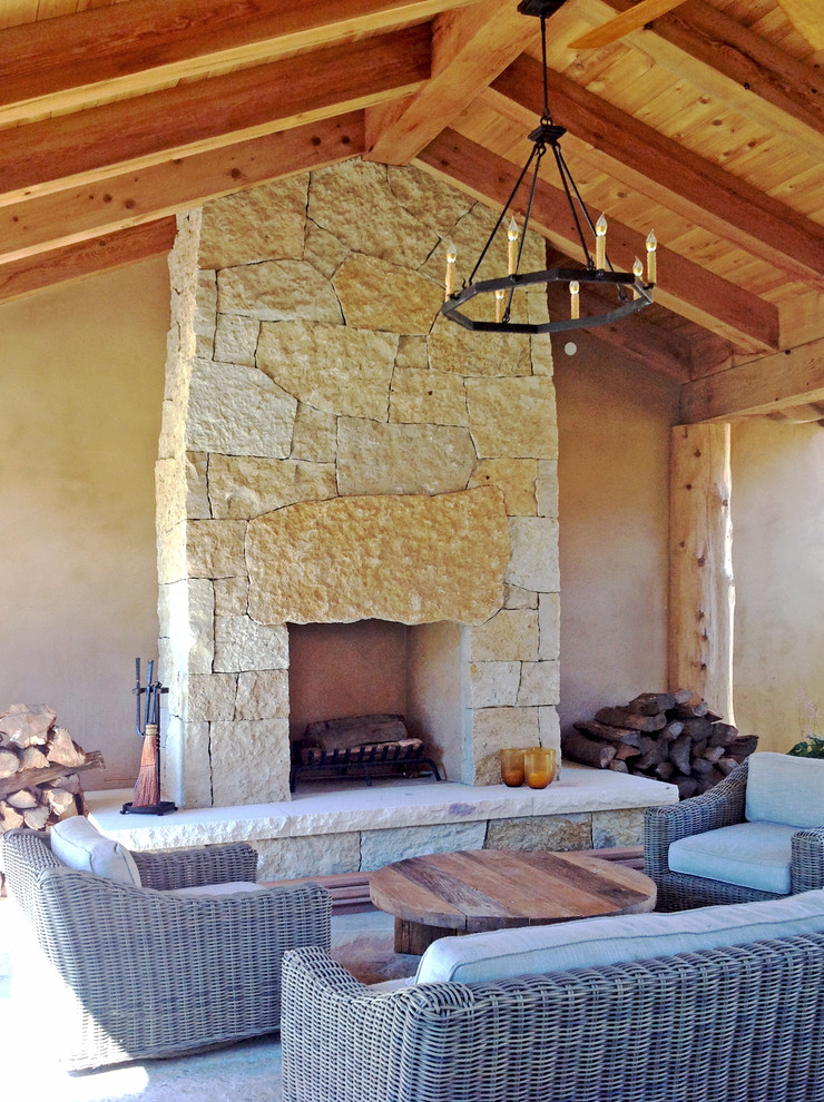 Inspiration for a large mediterranean patio in Other with a fire feature, natural stone pavers and a roof extension.