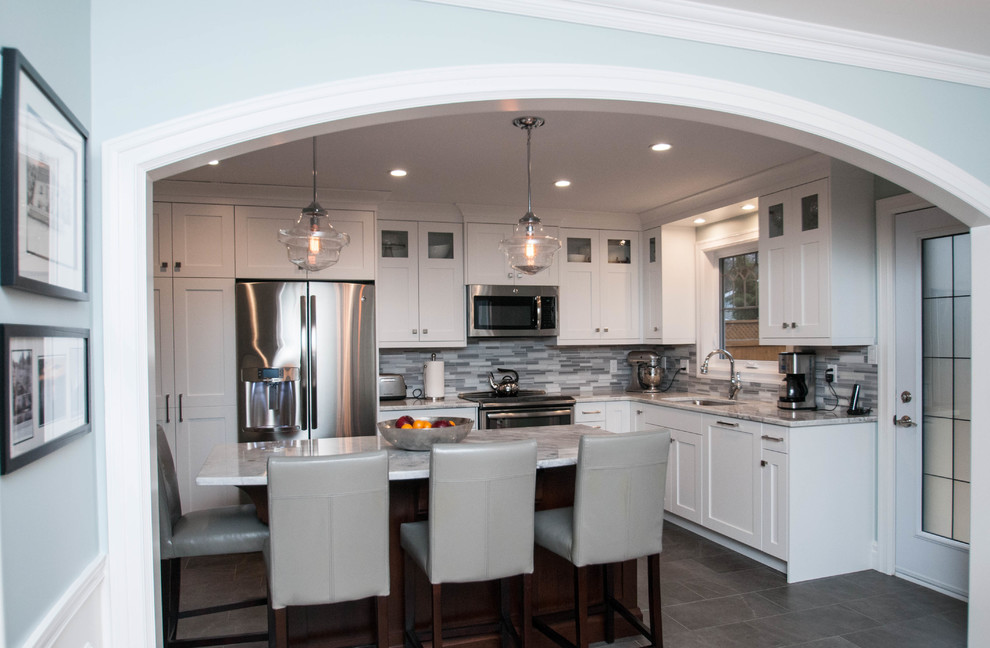 Inspiration for a mid-sized transitional l-shaped ceramic tile and gray floor eat-in kitchen remodel with an undermount sink, shaker cabinets, white cabinets, quartzite countertops, gray backsplash, stone tile backsplash, stainless steel appliances and an island