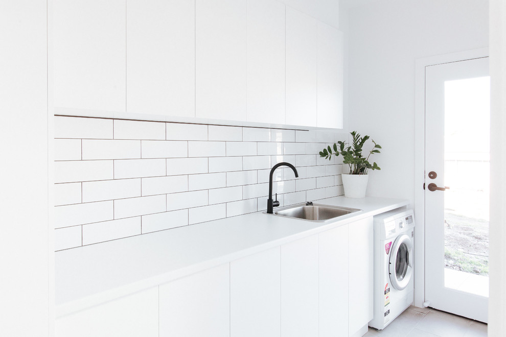 Design ideas for a mid-sized modern single-wall dedicated laundry room in Wollongong with a drop-in sink, flat-panel cabinets, white cabinets, laminate benchtops, white walls, ceramic floors, grey floor and white benchtop.