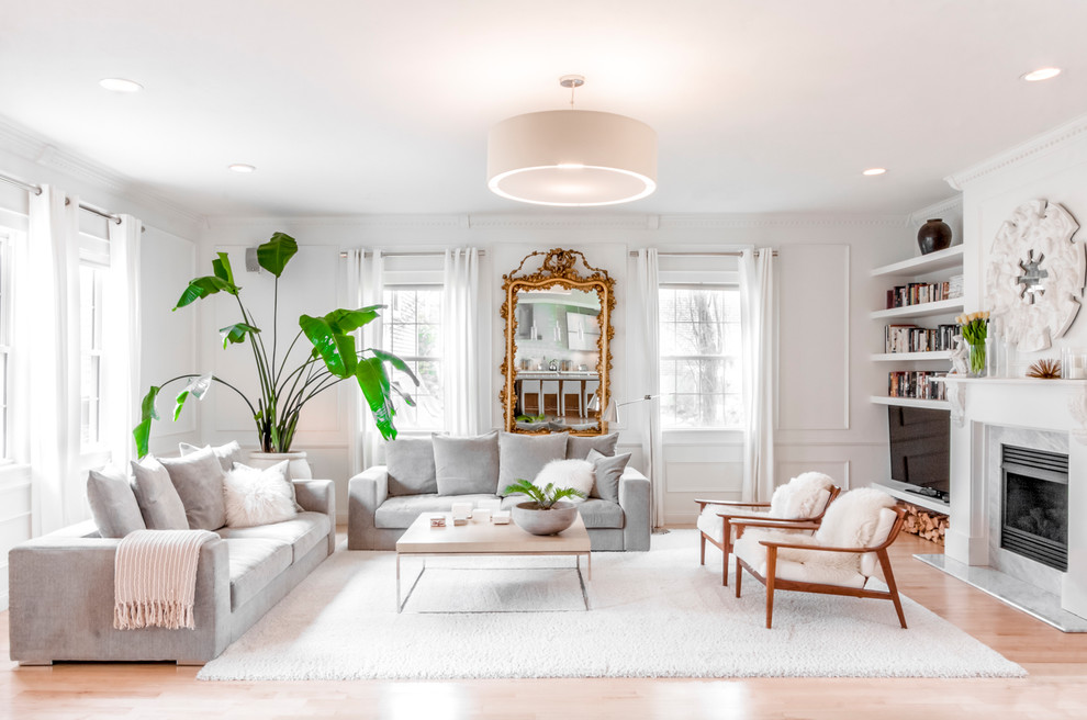 This is an example of a transitional living room in Boston with white walls, light hardwood floors, a standard fireplace, a freestanding tv and beige floor.